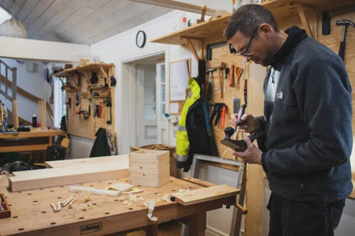Ein Mann arbeitet mit einem Werkzeug in einer Werkstatt in Capellagården