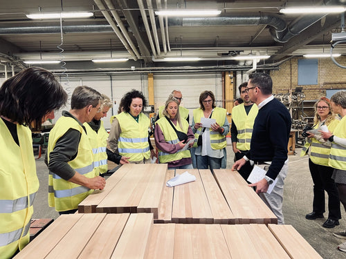 Lehrkräfte aus Amsterdam in gelben Westen bei einer Führung zwischen dem Holz in der Sjöbergs Fabrik