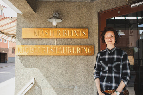 Pernilla Blixt vor dem Schild von Mäster Blixt Möbelrestaurering