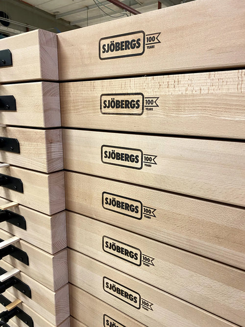 Gestapelte Holzkisten mit dem Sjöbergs 100-Jahre-Logo