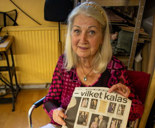 Inger Löwe hält einen Zeitungsartikel in ihrem Schneideratelier hoch