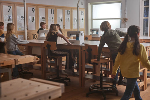 Schüler an Werkbänken und Nähmaschinen in einem Werkraum