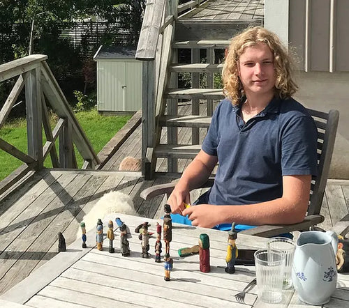 Adrian Nilsson Markung an einem Tisch mit seinen geschnitzten Holzfiguren