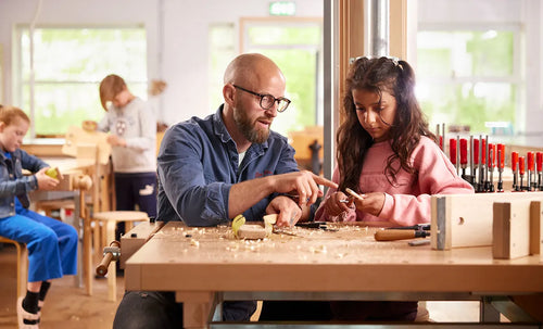 Ein Lehrer und Schüler arbeiten an einer Hobelbank in einem Werkraum