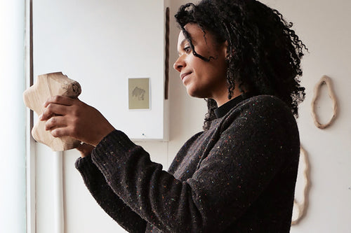 Sophie Sellu hält in ihrem Atelier eine Skulptur aus gespaltenem Holz hoch