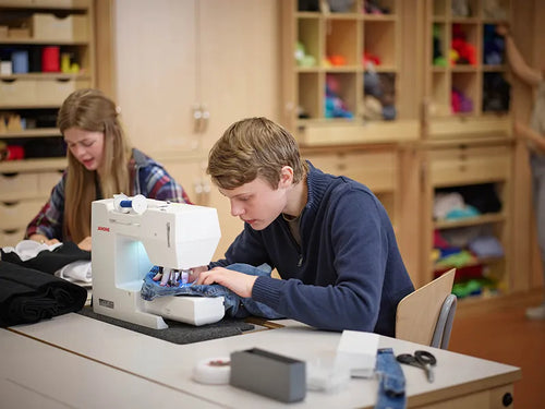 Schüler nähen an Nähmaschinen im Textilwerkraum